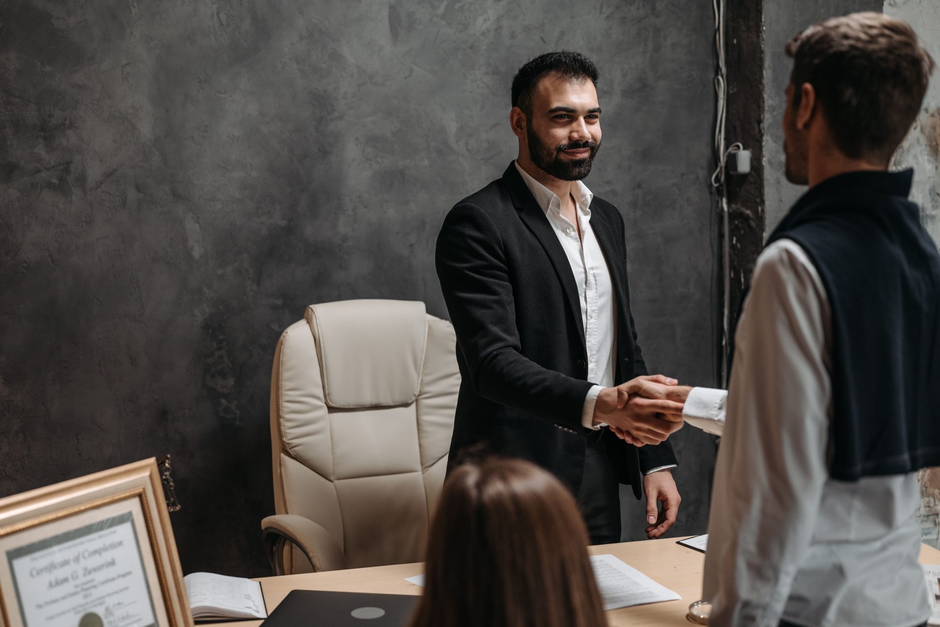 Businessmen in suits shaking hands in a professional office setting.
